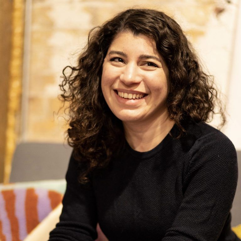 A photo of artist Frances Gallardo. She grins while looking off camera.