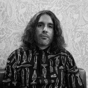 A grayscale headshot of artist Jonathan Torres. He looks at the camera with a neutral expression.