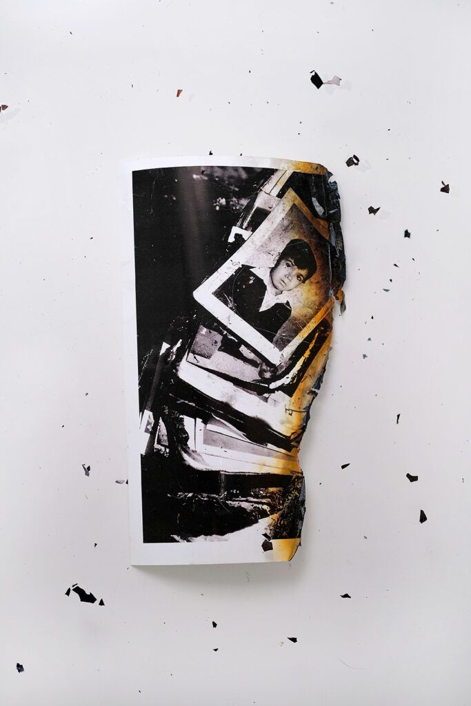 A burning photograph of Polaroid photos on a white table.