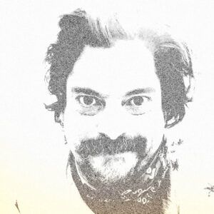 A close up photo of artist Efrén Candelaria. The image is high contrast and washed out. He looks intensely at the camera.