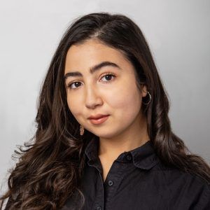 A close up photo of artist Gabby Vazquez smiling softly at the camera.