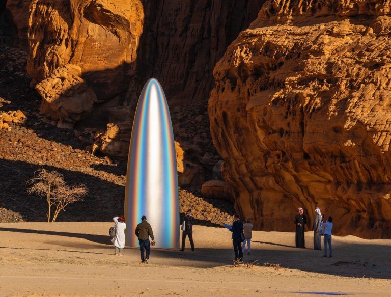 Large sculptural monolith made from engineered aerospace carbon fiber. It has a rainbow-colored sheen.