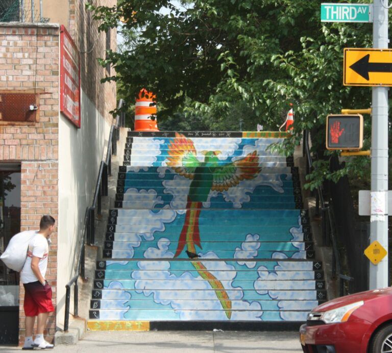 "'Rise Up,' by Josie Gonzalez, installed at Third Avenue and 164th Street, features a mythical bird that has elements of the Phoenix, Thunderbird, Puerto Rican parrot and Quetzal. The Taino-inspired pictographs in black and white on each side of the steps tell the story of her experience with painting this artwork, which she painted using a combination of masonry paint and spray paint." - Josie Gonzalez