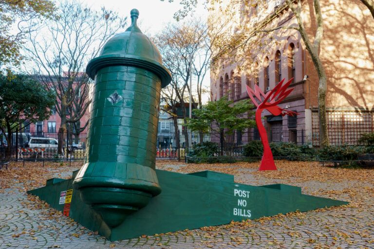 The work depicts the 13-foot tall guard tower (or garita in Spanish) from the colonial fortresses in Old San Juan, Puerto Rico, in the style of a New York construction site. The piece is at a 15-degree tilt, as though it is slowly sinking into the wave-like cobblestones of the park. Next to the work, is Growth, 1985 by Jorge Luis Rodríguez, a permanent sculpture and the first ‘Percent for Art’ commission in New York.
