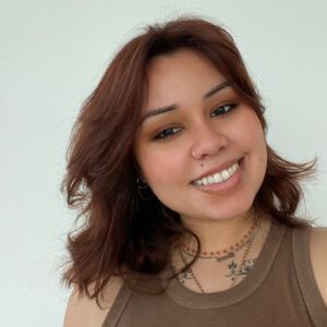 A close up photo of artist Marisol Ruiz. She looks towards the camera and grins.