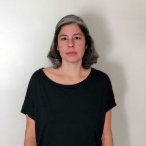 A photo of artist Monica Rodriguez. She looks at the camera with a neutral, open expression.