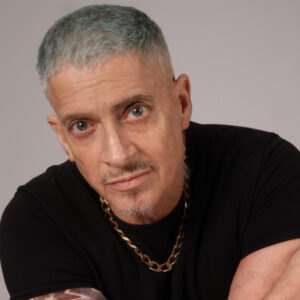 A close up photo of artist Luis Carle. He looks directly at the camera with a neutral, open expression.