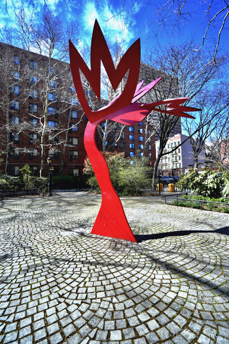 Freestanding red painted steel sculpture that looks like flowers growing from the earth.