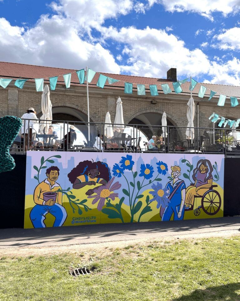 Four people in a garden appreciating the plants. There are bright flowers painted in the center.