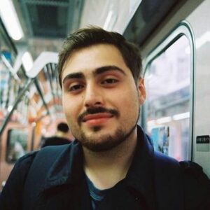 A close up photo of artist Joseph Kattou on public transit. He smiles at the camera.