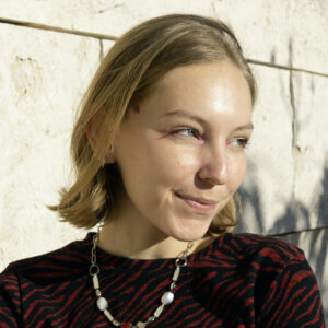 A close up photo of artist Isabela Miñana Lovelace. She smiles while looking away from the camera.