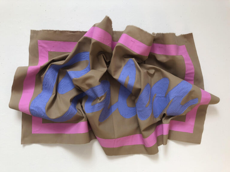 The word "Calm" in blue paint surrounded by a pink border on brown canvas. The canvas is crumpled but the word is still legible.
