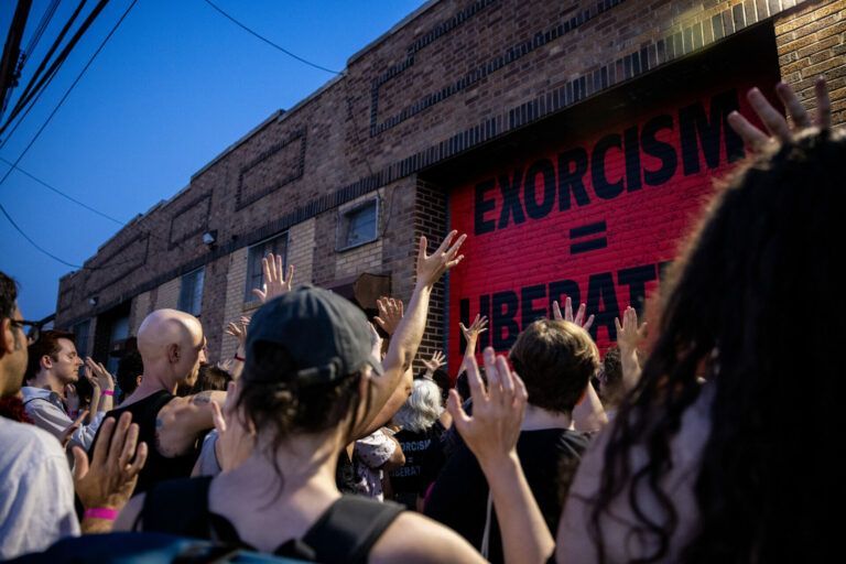 Public art installation with black words " Exorcism = Liberation" on a red background.