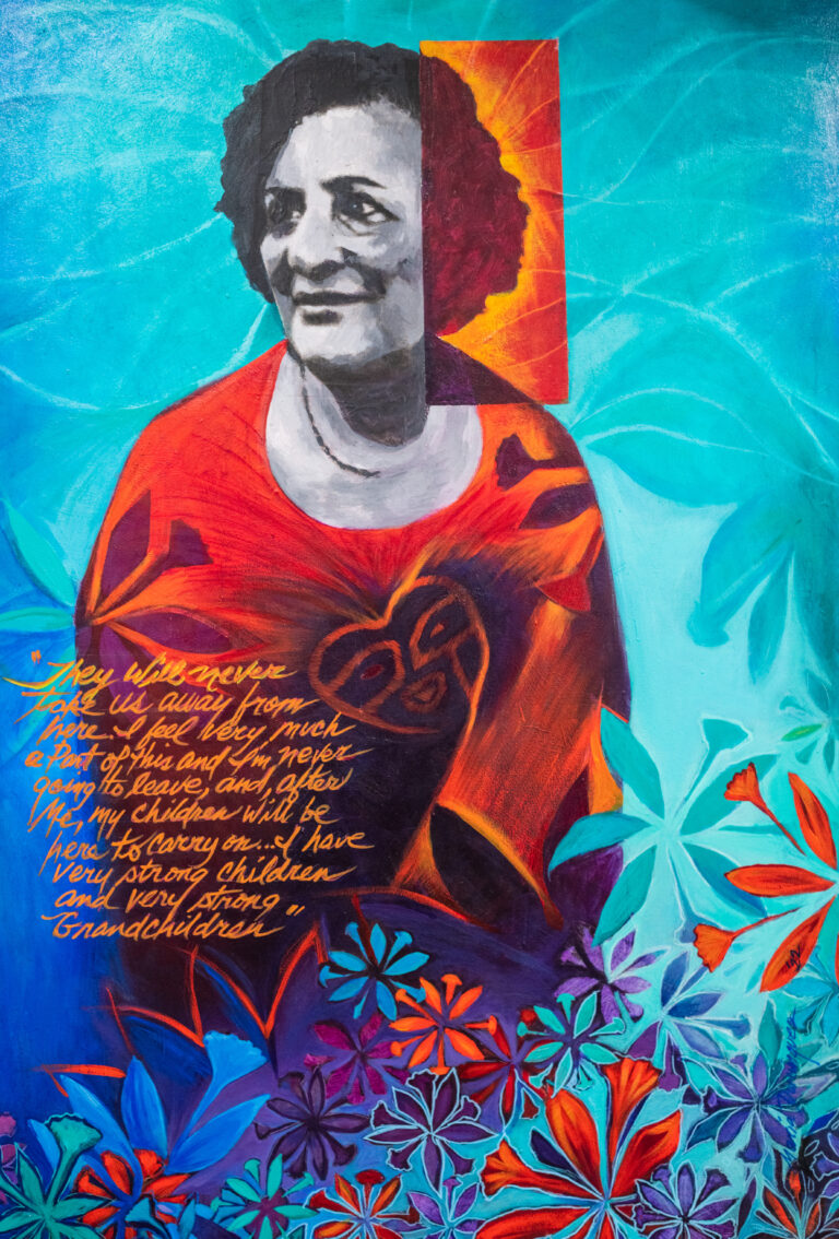 Colorful portrait of a woman surrounded by florals with Taino symbol on her chest. "They will never take us away from here. I feel very much a part of this and I'm never going to leave, and, after me, my children will be here to carry on... I have very strong children and very strong grandchildren"