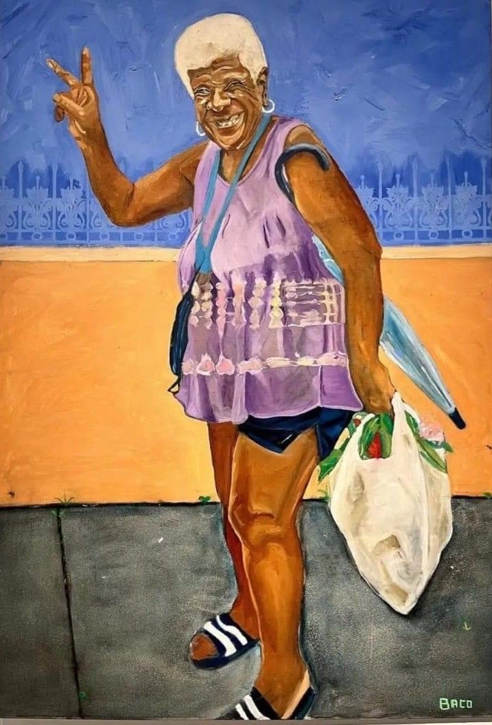 Older woman with mid-tone skin and white hair gives a peace sign and a smile at the viewer. She holds a few bags and a closed umbrella.