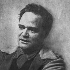 An old, grayscale close up photo of artist Juan De'Prey. He looks away from the camera with a neutral expression.