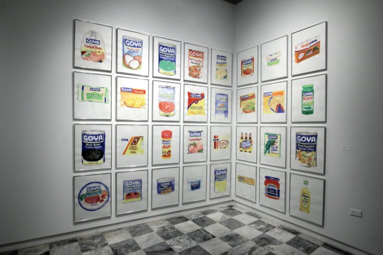 Large drawings of Goya goods in a 4 x 5 grid of frames on the left wall and 4 x 3 on the right wall as if 4 x 8 display was folded into the corner of the installation. Featured products such as black beans, adobo, oil, salt, corned beef, and more.