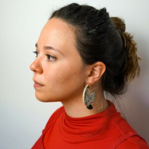 A close up photo of artist Laurie De Jesús Lagares. She faces away from the camera with a neutral expression.