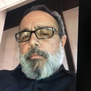 A close up photo of artist Bruno Casiano. He wears glasses and looks at the camera with a neutral expression.