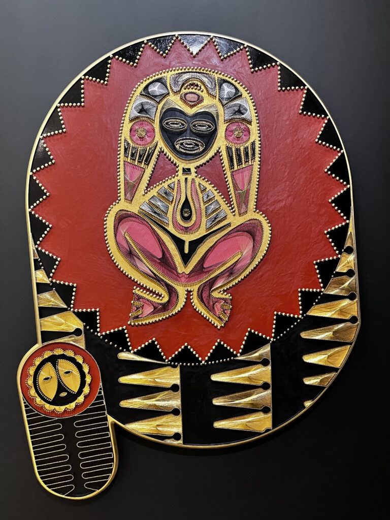 "Here, we encounter a sculpture of the ancestral mother Atabey, constructed using hammered nails." - Glendalys Medina. The goddess figure sits in the middle of a red star shape surrounded by a black trim.