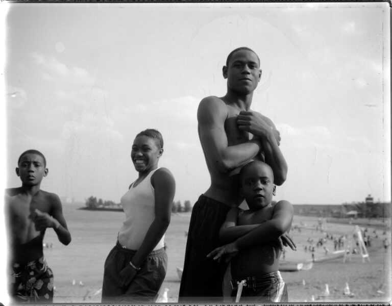 Four people at the beach posing for a picture. Two adults and two children.