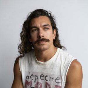 A photo of artist Juan Antonio Olivares. He looks away from the camera with a neutral expression.