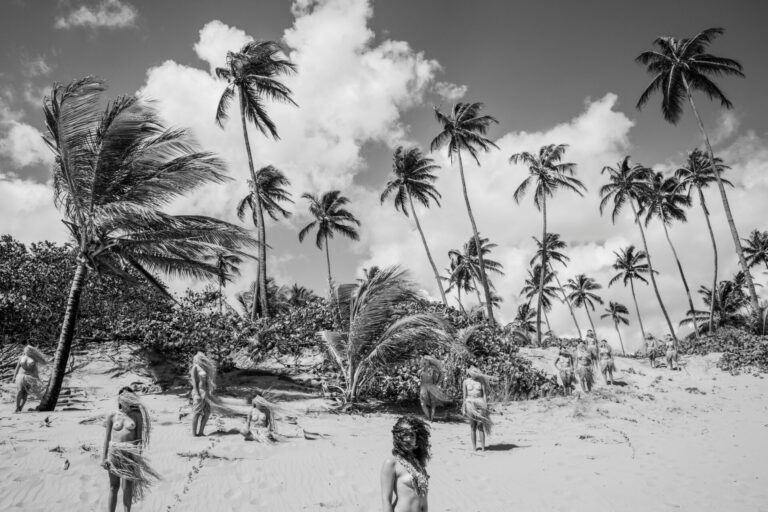 Partially nude women stand on the beach in this black and white photo.