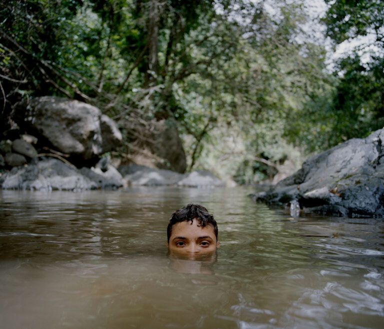 "My cousin, Eliam, cools off in a small pool of water after hiking down from our grandfather Horacio’s home, in the barrio of Dajaos. The barrio is named after the small fish that frequent the streams in the area. Villalba, Puerto Rico, July 2018."