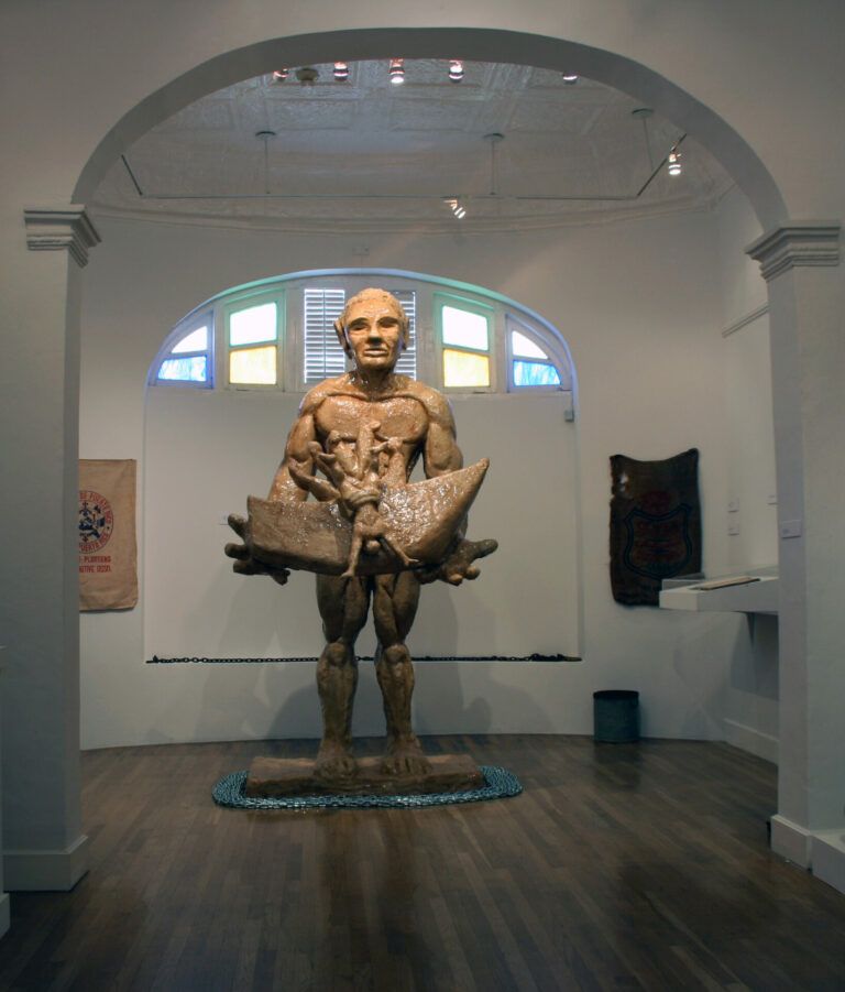 A tall statue representing the abolition of slavery. A human figure stands with chains surrounding his feet and a heavy form in his hands.