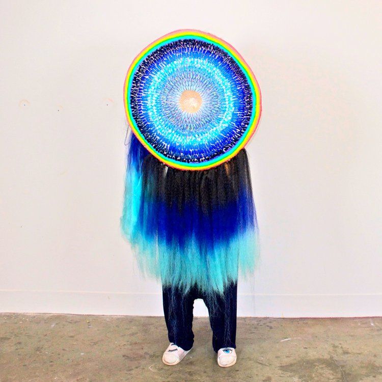 A rainbow-outlined circular "shield" with blue colorful hair coming out of the bottom.