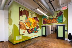 Mural of people cooking. Food is in spoons and bowls.