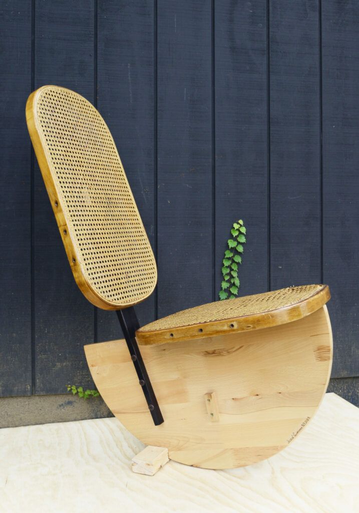 A wooden rocking chair that is rounded and could tip over easily.