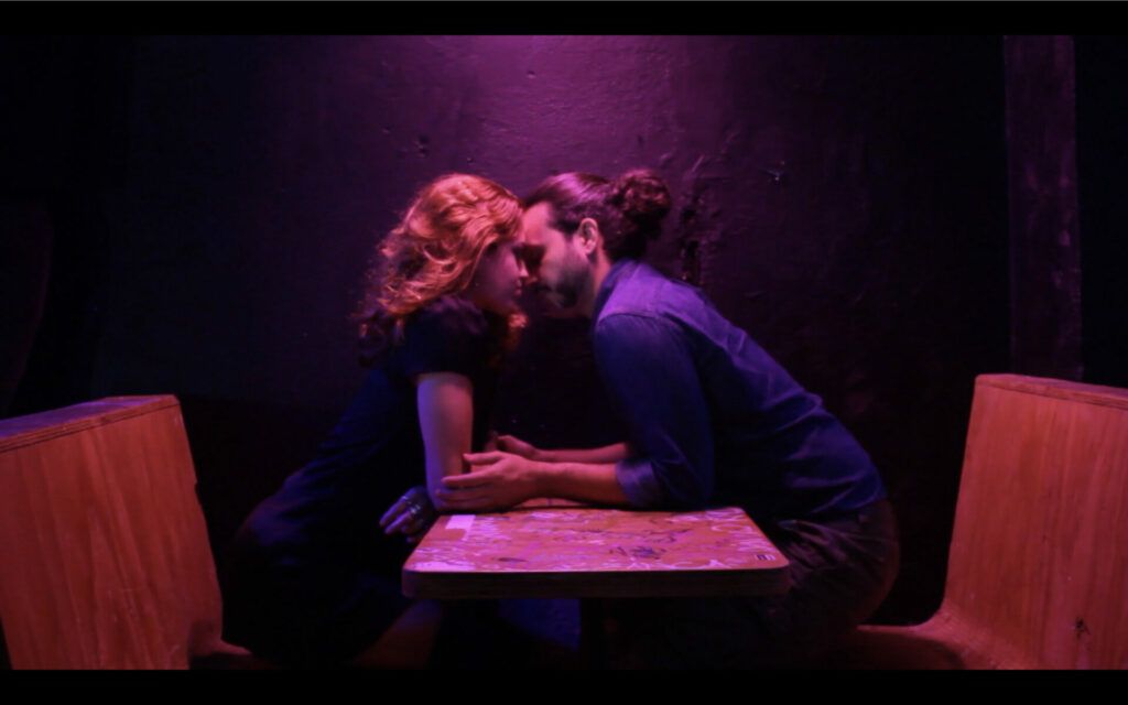 Scene that displays "bisexual lighting" (blue, pink) as two characters embrace.