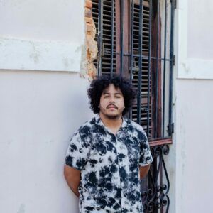 Luis Rivera Jimenez standing in front of an old colonial window with bars.