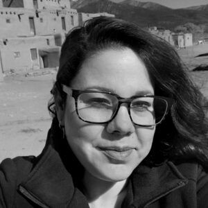 Black and white photo of Tamara Cedre with glasses and long hair.