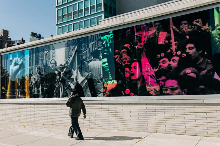 Images of Hiram Maristany on colorful glass like a mural on the street.
