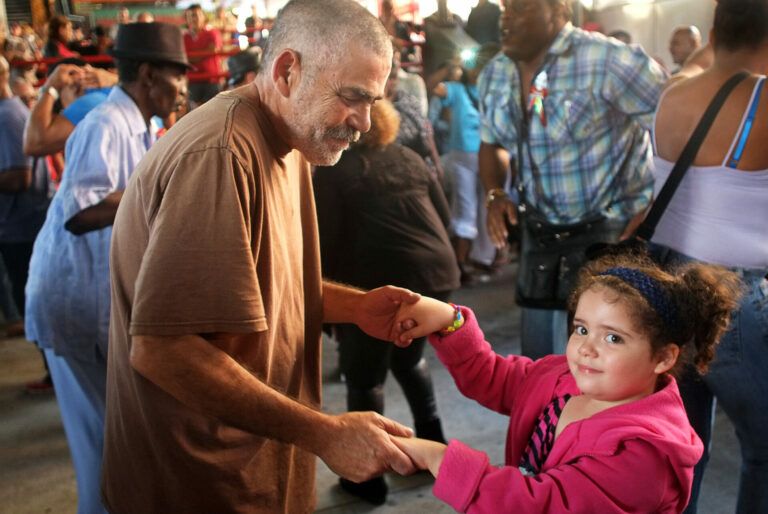 An older man and a young girl dancing together.