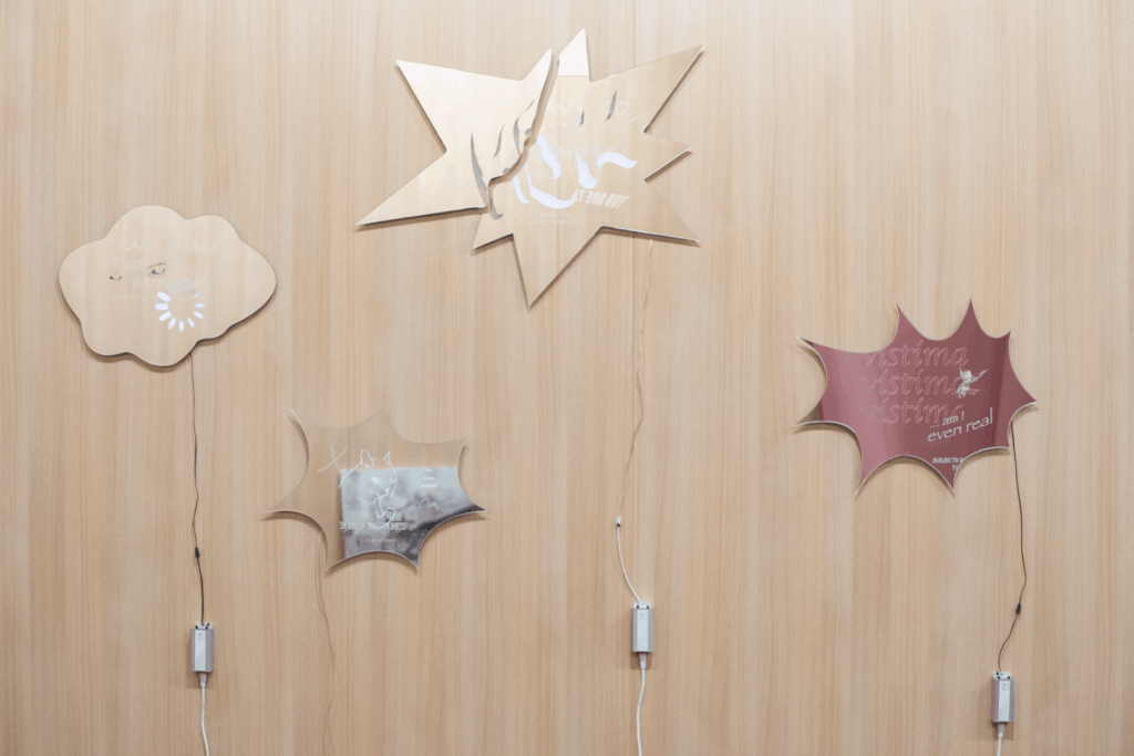 Engraved glass on wooden wall. Each piece of glass has a drawing or messages on it, accompanied by a backlight.