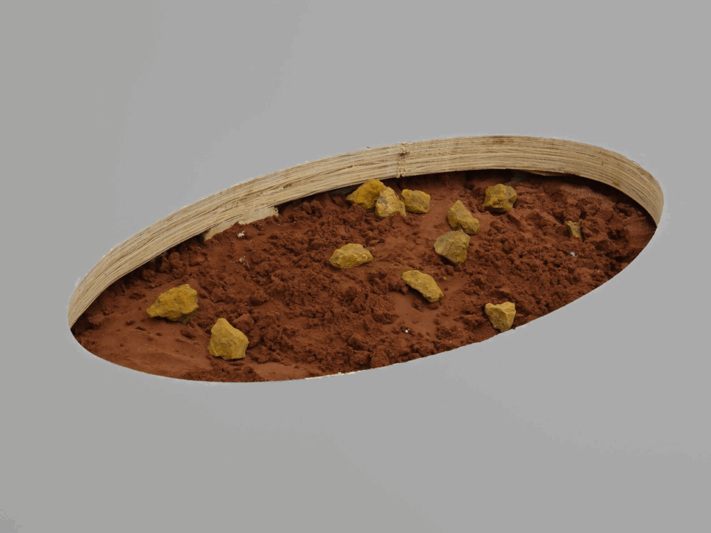 An ellipse cut from the gallery floor to reveal red earth.