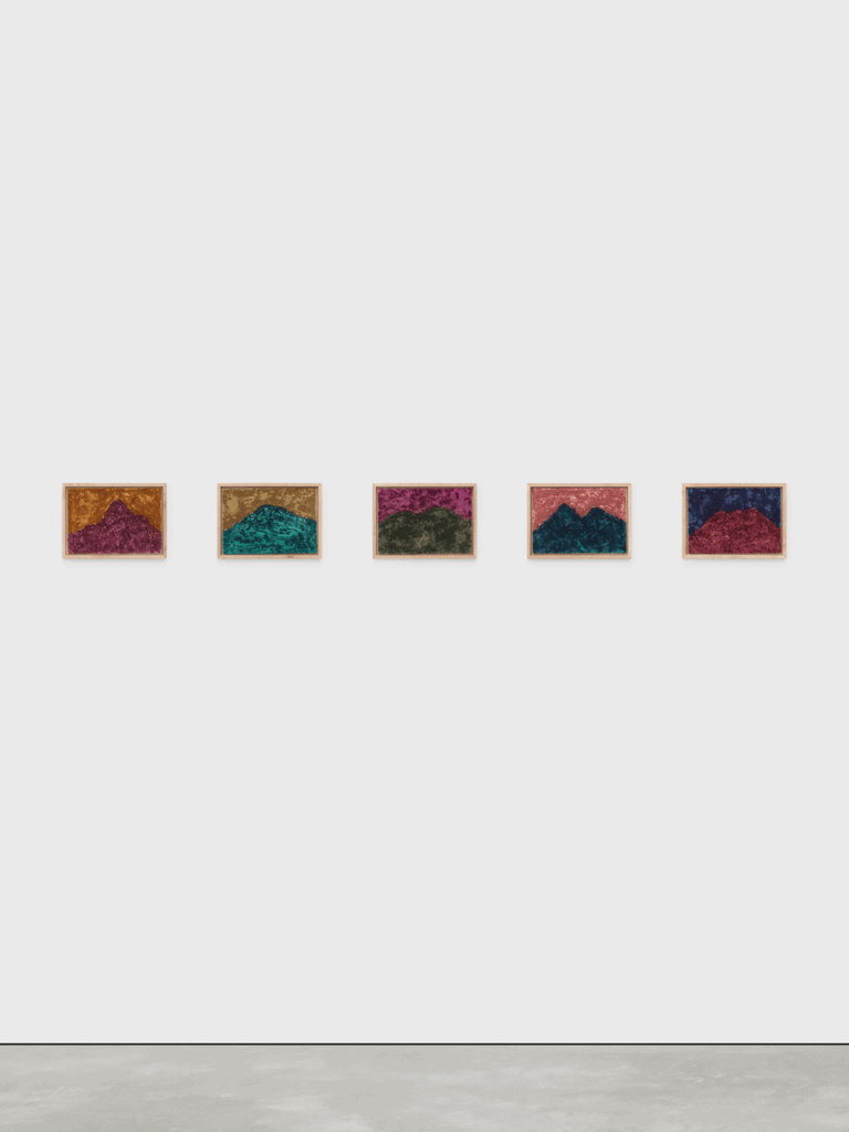 Five framed landscape paintings lined up on a wall. Each one is a mountain painted in an unnatural color with a corresponding unnaturally colored sky.