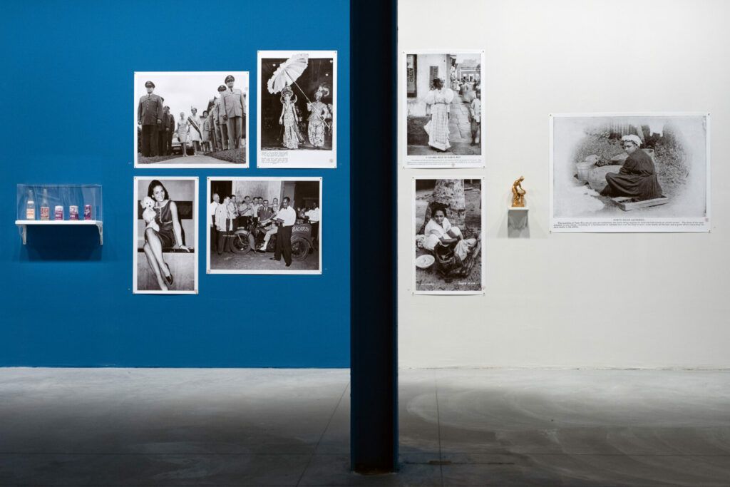 Blue and white exhibition wall displaying Pablo Delano photographs and a clear case of vintage drink bottles.